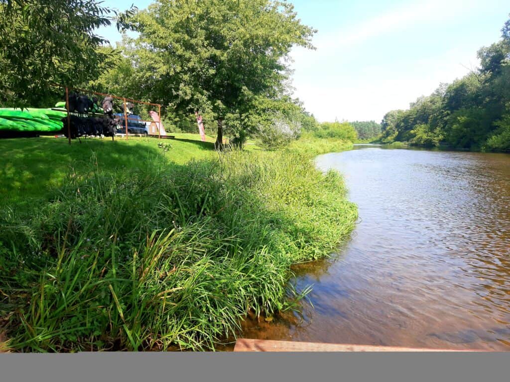 Grupa osób na łódce z AQUASURF, wypożyczalnia kajaków na rzece.